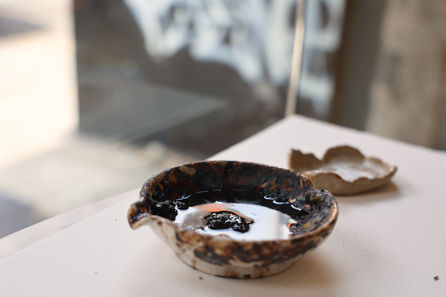 A small brown bowl sits on a table half full with water